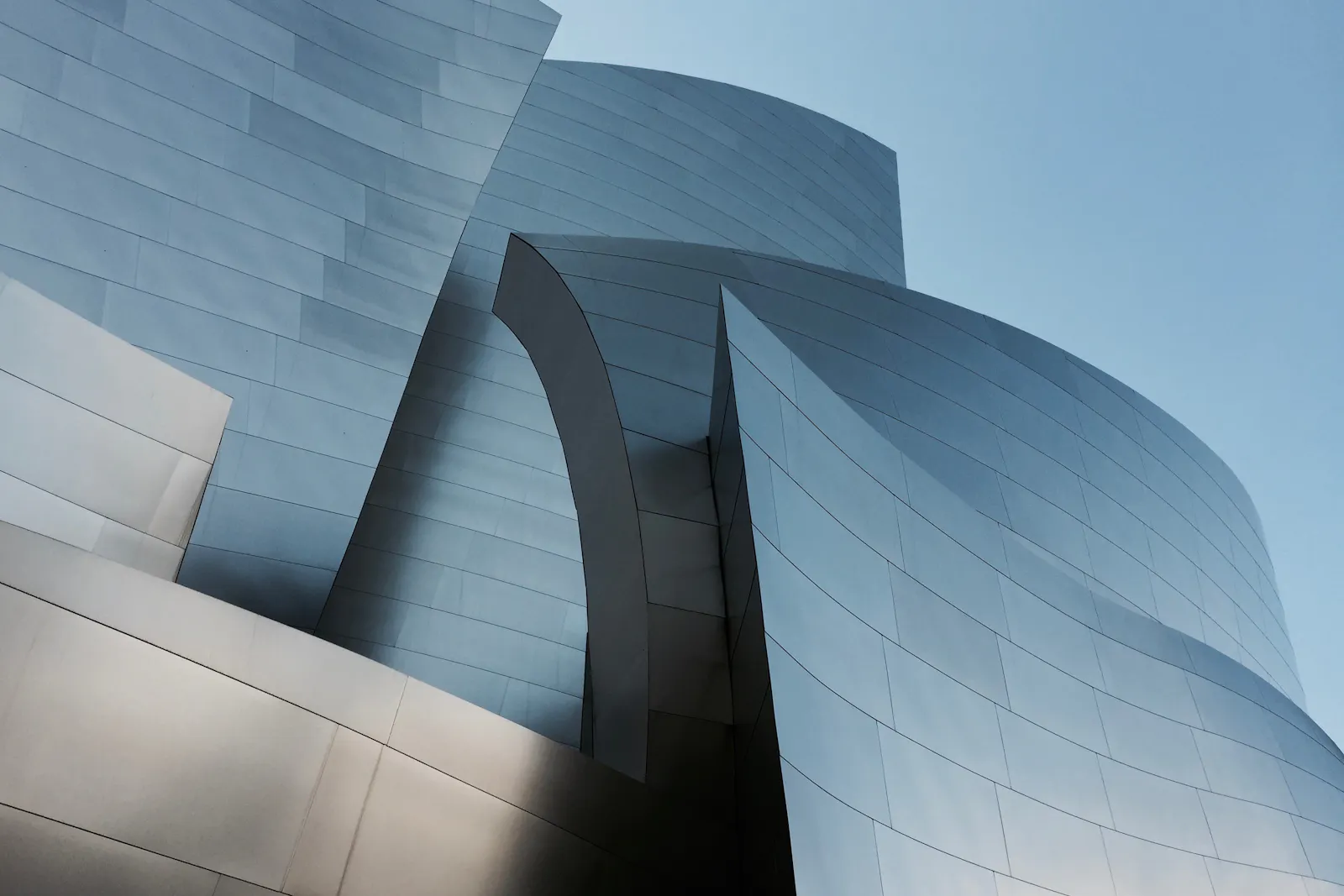 Overlapping curved metal panels catching soft light.