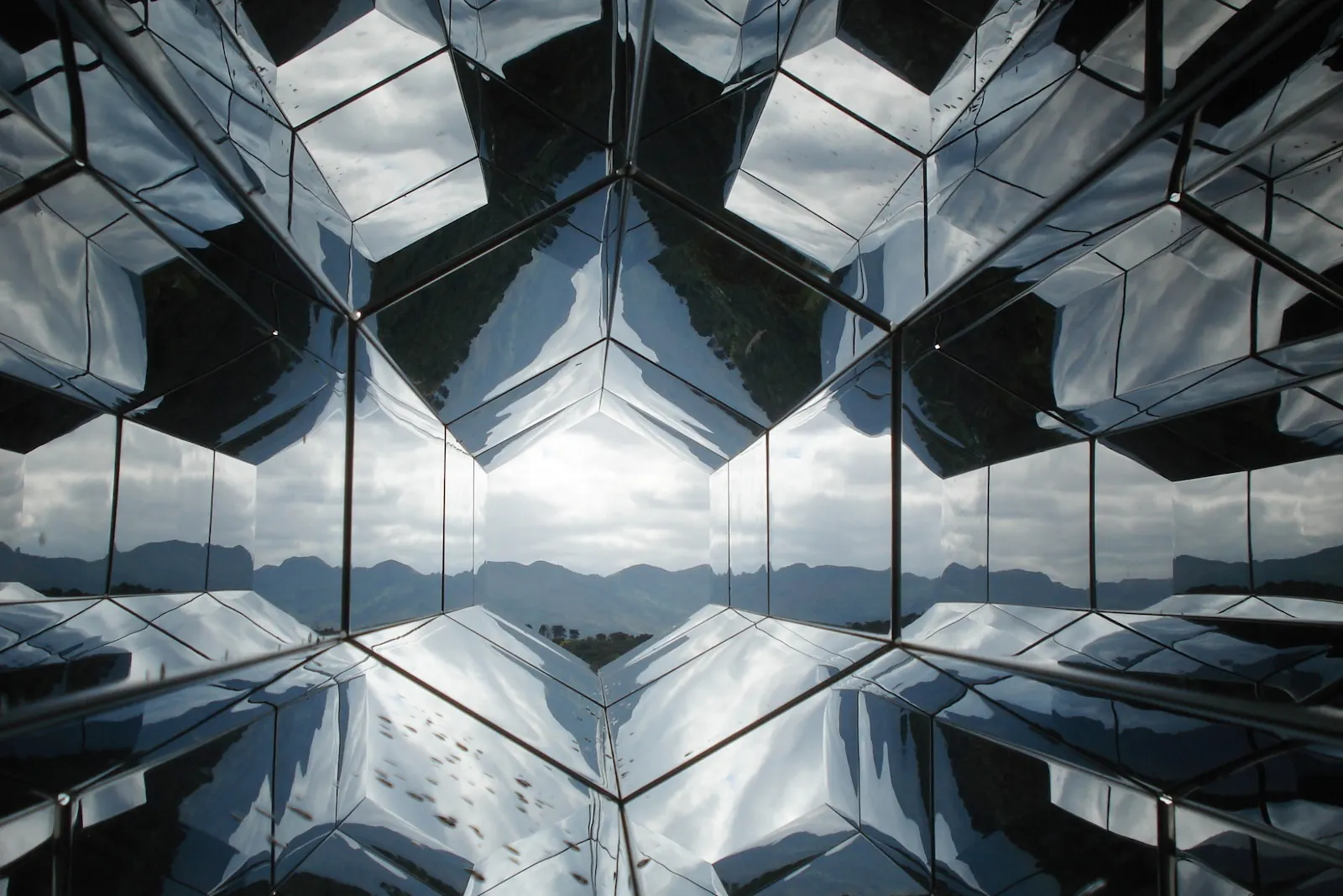 A mirrored tunnel framing mountains in the distance.