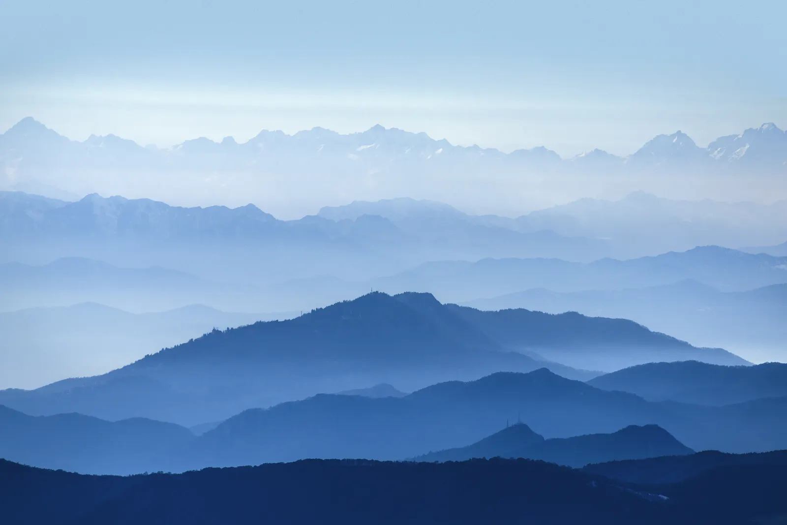 Layers of blue mountain ridges beneath a clear sky.
